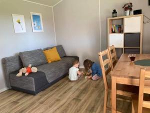 two children sitting on the floor in a living room at Domki na Mazurach "Malinka" in Suchy Róg +7 photos
