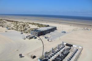 a beach with a building on the sand and the ocean at Sailer 5A - De Panne in De Panne