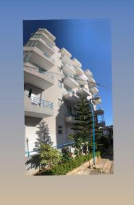 un edificio de apartamentos blanco con un árbol delante en Ernest Apartments, en Sarandë