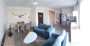 a living room with a blue couch and a kitchen at Apartamenty Marynarki Wojennej, Dziwnów in Dziwnów