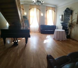 a living room with a piano and a couch at Sventes Muiža in Svente