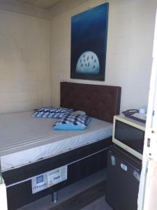 um pequeno quarto com uma cama e uma televisão em Suíte Independente em Arraial do Cabo