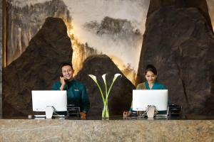 duas pessoas sentadas numa secretária com os seus portáteis em The Manohara Hotel Yogyakarta em Yogyakarta