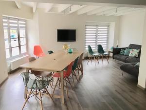 een woonkamer met een tafel en stoelen en een bank bij La Maison du Bonheur - Grande maison de vacances classée 4 étoiles in Le Boupère