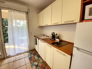 uma cozinha com armários brancos e um frigorífico em Appartement 2 pièces au cœur du Cap d'Antibes em Antibes