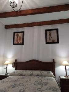ウベダにあるAlojamientos Turísticos Delgadoのベッドルーム1室(ベッド1台付)が備わります。壁に2枚の写真が飾られています。