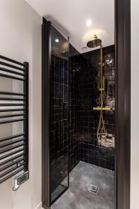 a bathroom with a shower with black tiles at CMG Notre-Dame / Ile de la CIté in Paris