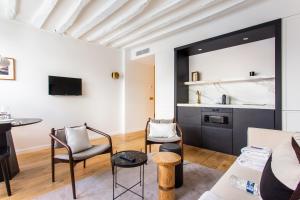 a living room with a couch and chairs and a kitchen at CMG Notre-Dame / Ile de la CIté in Paris