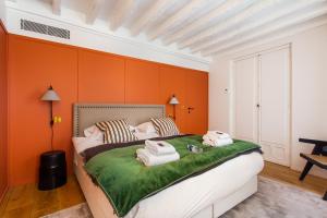 a bedroom with orange walls and a bed with towels on it at CMG Notre-Dame / Ile de la CIté in Paris