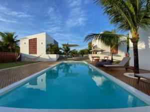einen Pool mit Palmen und ein Haus in der Unterkunft Maison dos Corais in São Miguel do Gostoso