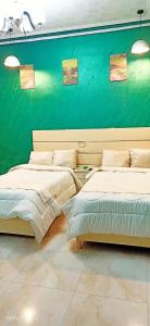 My place agata Hostel في القاهرة: سريرين في غرفة ذات جدار أخضر