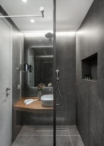 a bathroom with a shower with a sink and a mirror at DAYS City Suites in Patra