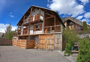 a large wooden house with a balcony on a driveway at Serre Che Chalet in Briançon