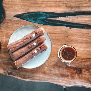 two hot dogs on a plate next to a cup of coffee at Sharz Hotel in Buraydah