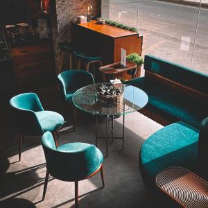 a cafe with green chairs and a glass table at Sharz Hotel in Buraydah