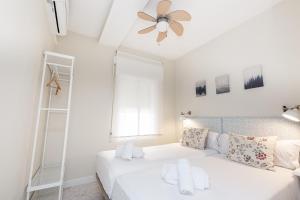 een witte slaapkamer met een bed en een plafondventilator bij MONKÓ - 1 LINE, BEACH & SUN in Torremolinos