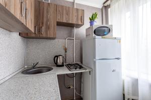 una pequeña cocina con fregadero y nevera. en Standard Brusnika Apartment on Eniseyskaya, en Moscú