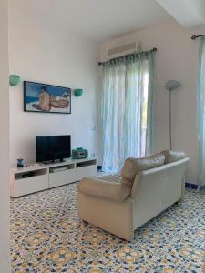 uma sala de estar com um sofá e uma televisão de ecrã plano em B&B La Marinella em Palinuro