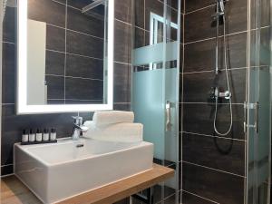 La salle de bains est pourvue d'un lavabo et d'une douche. dans l'établissement Hôtel Clairefontaine, à Paris