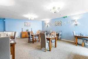 a dining room with tables and chairs and a blue wall at Mount Edgcombe in Torquay