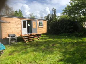 een klein huisje in een grasveld met een deur bij Tiny house op wielen Friesland in Workum