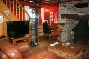 een woonkamer met een televisie en een open haard bij Barn Cottage - Farm Park Stay with Hot Tub in Swansea