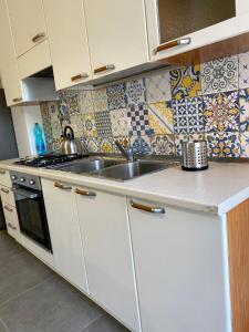 a kitchen with white cabinets and a sink at Le Sorelle Apartment in Agrigento