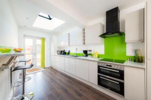 una cocina con armarios blancos y detalles verdes en Hepburn House 4 Bedroom Property - Stayseekers, en Salisbury