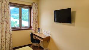 ein Hotelzimmer mit einem Schreibtisch und einem TV an der Wand in der Unterkunft Hotel Casa do Tua in Foz Tua