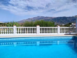 a white fence next to a swimming pool with mountains at B&B la Madrugada in Cómpeta