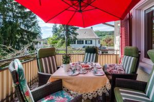 einen Tisch auf einem Balkon mit einem roten Regenschirm in der Unterkunft Flair Ferienwohnung Orchidee in Stockach