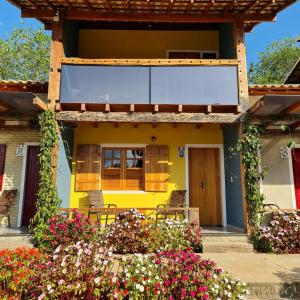 a yellow house with flowers in front of it at Pousada Vila Mandalah in Carrancas