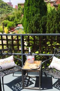 einen Tisch und Stühle auf einem Balkon mit einer Flasche Wein in der Unterkunft Bakers Cottage in Ironbridge