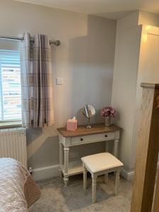 a bedroom with a dressing table with a mirror and a stool at Bakers Cottage in Ironbridge