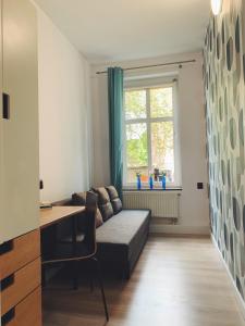 a living room with a couch and a desk and a window at Rooms4Less in Gdańsk