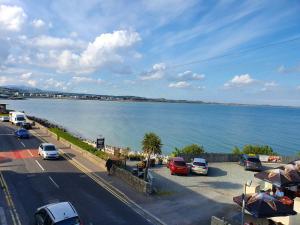 a road with cars parked next to a body of water at Seafront Apartment in Newcastle