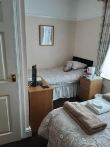 a bedroom with two beds and a desk and a window at Chantry Villa Hotel in Skegness