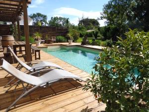 a swimming pool with chairs on a wooden deck at Mas des Rabasses in Le Pontet