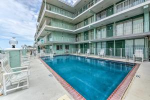 a large swimming pool with chairs and a building at Stunning Beachfront Condo with Panoramic Ocean View in Wildwood Crest