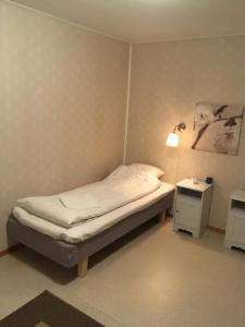 a small bedroom with a bed and a lamp at House in the heart of Lapland P4 in Puoltikasvaara