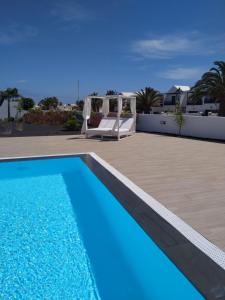 a blue swimming pool with a deck and a patio at Apartment El Sueño - GREAT SEA VIEWS - SWIMMING POOL - free Wifi- smart TV-Residence SENATOR el majo in Costa Teguise