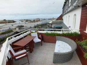 eine Terrasse mit einem Tisch, Stühlen und Meerblick in der Unterkunft Hôtel - Restaurant - Salon de Thé Le Beauséjour in Trégastel