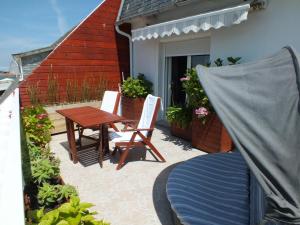 een patio met een houten tafel en stoelen en een huis bij Hôtel - Restaurant - Salon de Thé Le Beauséjour in Trégastel