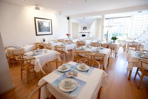 a restaurant with white tables and chairs and windows at Hotel Van Bunnen in Knokke-Heist