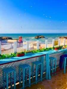 una mesa con taburetes azules frente a la playa en Riad Lunetoile, en Essaouira