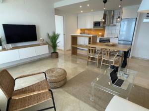 a living room with a table and a kitchen at Mediterraneo Sitges in Sitges