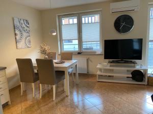 a dining room with a table with chairs and a television at Apartament Zielone Tarasy 7B in Kołobrzeg