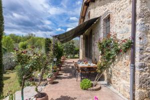 eine Terrasse mit einem Tisch und Stühlen in einem Steingebäude in der Unterkunft Casa vacanze San Giusto in Sovicille