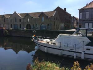 a white boat sitting in the water in front of buildings at COTTAGE ON THE CANAL in Kortrijk