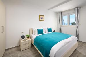 a white bedroom with a large bed and a window at Villa Ivano in Makarska